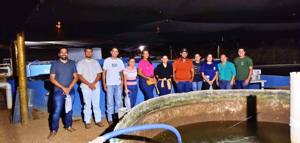 Alunos posam para foto em frente ao tanque de criação de peixes